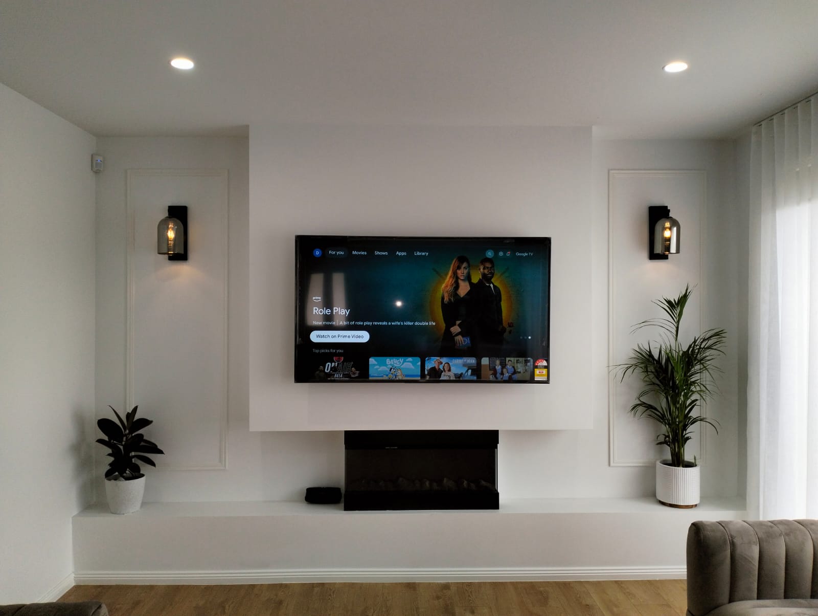 Minimalist living room with a wall-mounted TV, built-in fireplace, and decorative wall sconces.